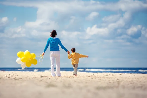 Familj med gula ballonger på stranden — Stockfoto