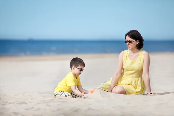 Joven madre e hijo jugando en la playa de arena —  Fotos de Stock