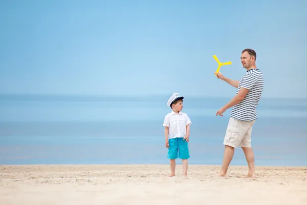 Far och son spelar tillsammans på stranden — Stockfoto