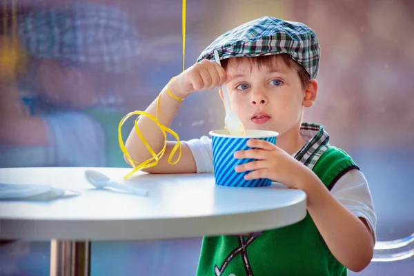 Bonito menino comendo sorvete no café interior — Fotografia de Stock