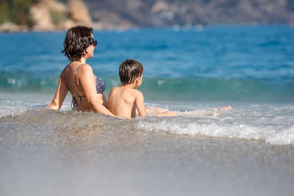 Mãe e filho salpicando nas ondas do oceano — Fotografia de Stock