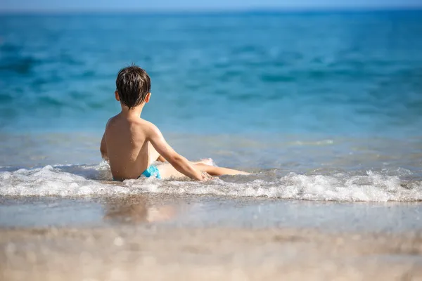 Kleine jongen spatten in de oceaan golven — Stockfoto