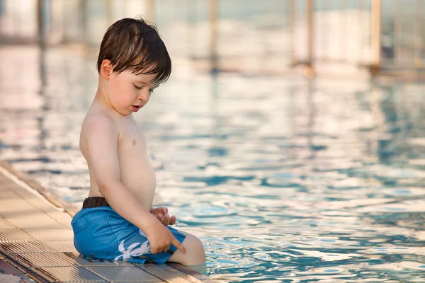 Cute toddler boy sitting by a swimming pool — Stock Photo, Image