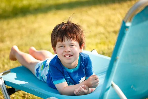 Niedliche Kleinkind Junge sitzt auf einer Sonnenbank — Stockfoto