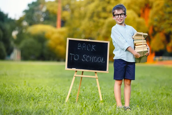 Симпатичный школьник с большой стопкой книг — стоковое фото