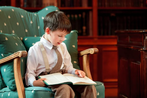 Mignon petit garçon lecture livre sur fauteuil — Photo