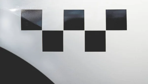 Black Checker Pattern on a white taxi car. Checker Pattern closeup. Taxi, taxicab sign. Dusty taxi surface. Black and white checker taxi. Space for text.