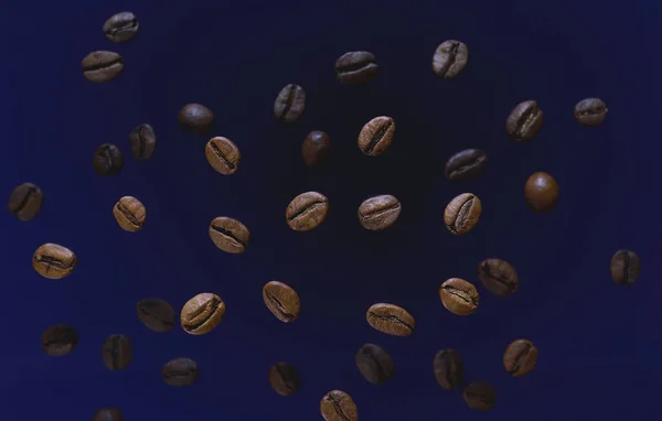 咖啡豆顶部可以看到蓝色背景 咖啡豆洒了分散的咖啡粒 飞咖啡豆 咖啡因 新鲜的味道 早晨清爽饮料配料 免版税图库照片