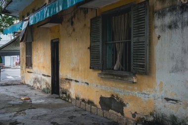 Terk edilmiş eski bir ev. Dış görünüş. Pejmürde bir binanın klasik kepenkli penceresi. Doğal afet, kasırga ya da sel sonrası.