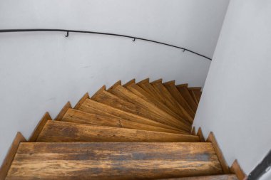 Özel bir evdeki ahşap bir sarmal merdivenin en üst görüntüsü. Beyaz duvarlar