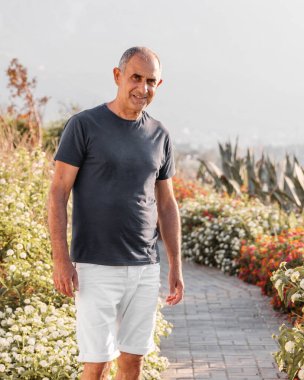 Dışarda duran 60 yaşındaki gülümseyen bir adamın portresi.