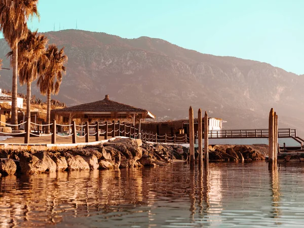 Topical landscape, sea, mountains, bungalows, bridge and palm trees on summer beach — Stock Photo, Image