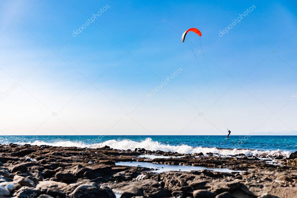 A man kiteboarding on sea water on blue sky background. Kitesurfing on Cyprus.