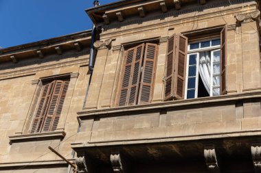 Eski bir binada, tahta panjurları ve beyaz dantel perdeleri olan pencereleri aç..