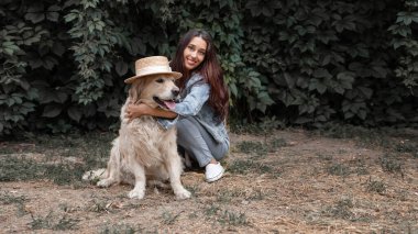Portrait of young smiling woman cuddling her dog golden retriever labrador outdoor
