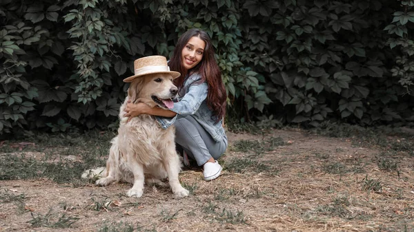 Portrait of young smiling woman cuddling her dog golden retriever labrador outdoor