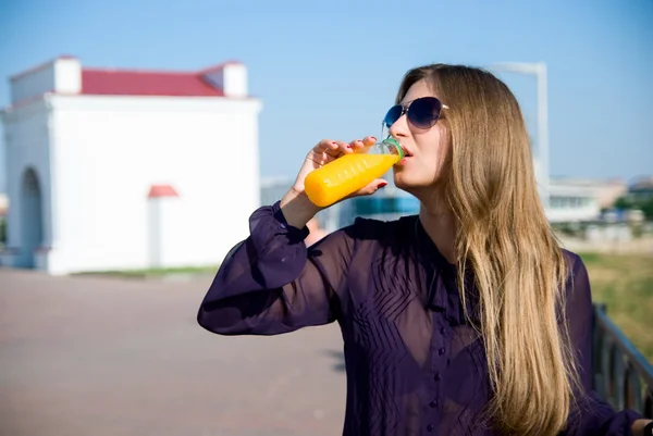 Woman in dark glasses drinks orange drink — Stock Photo, Image