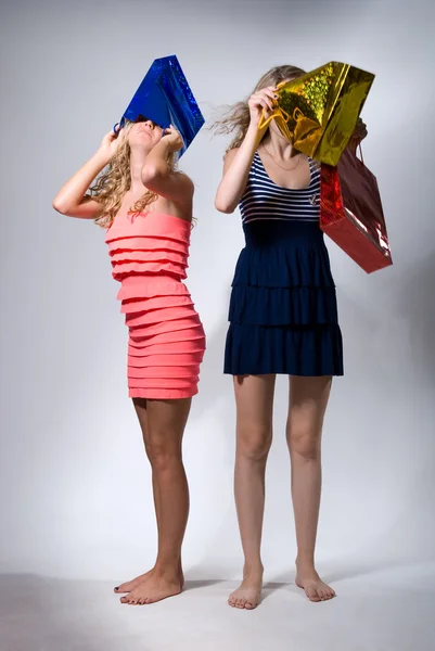 Dos muchachas ponen en cabezas paquetes multicolores para las compras —  Fotos de Stock