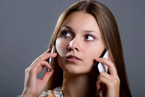 Junge Geschäftsfrau mit zwei Mobiltelefonen im Gespräch. — Stockfoto