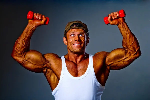 Musculoso hombre entrenamiento con pequeñas mancuernas — Foto de Stock