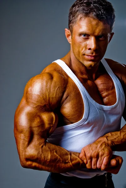Un hombre muestra sus músculos en el estudio —  Fotos de Stock
