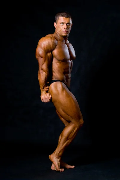 Bodybuilder posing on black background — Stock Photo, Image
