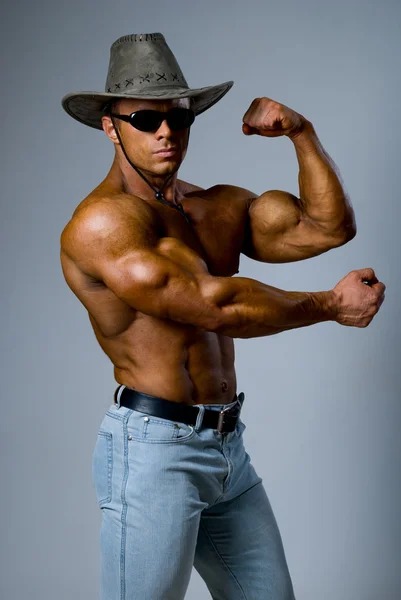 在一顶帽子，展示他的肌肉肌肉帅哥 — 图库照片
