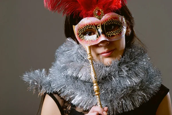 Retrato de cerca de una niña en una máscara con plumas rojas y latas — Foto de Stock