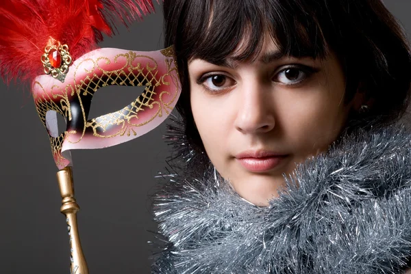 Gros plan portrait d'une fille dans un masque avec des plumes rouges et des boîtes — Photo