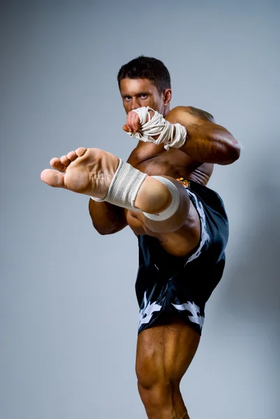 Kick bokser kopnięcia na szarym tle. — Zdjęcie stockowe