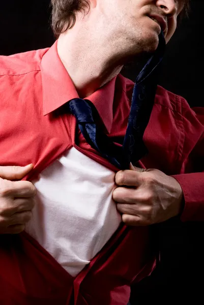 Uomo arrabbiato strappa una camicia rossa su uno sfondo nero — Foto Stock