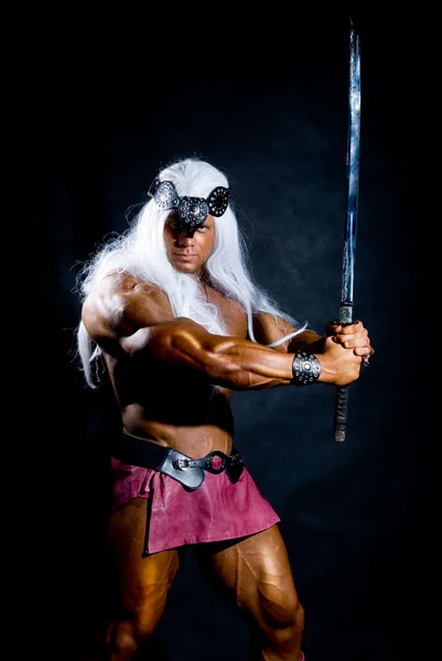 Hombre musculoso en una imagen de un bárbaro con una espada levantada . — Foto de Stock