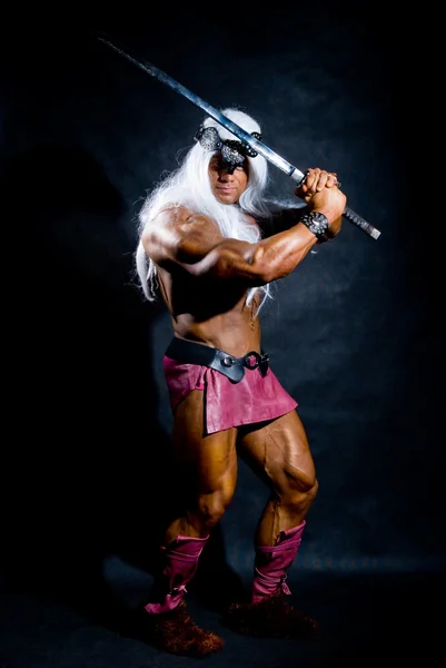 Muscular man in an image of a barbarian with a raised sword. — Stock Photo, Image