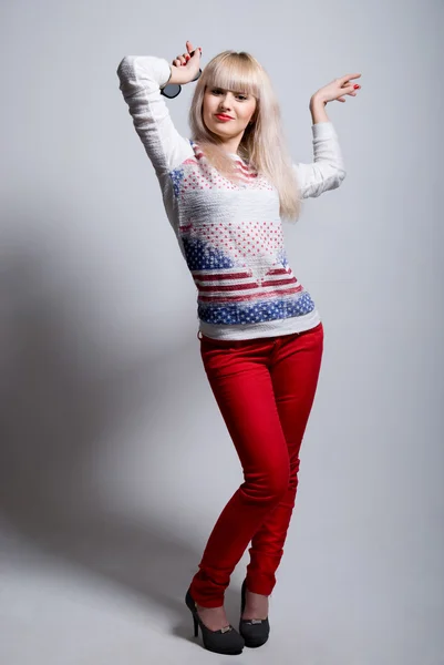 Sexy playful young blonde in a red jeans — Stock Photo, Image