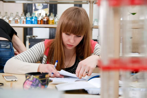 En student vid arbete i laboratorium av kemi studerar poster — Stockfoto