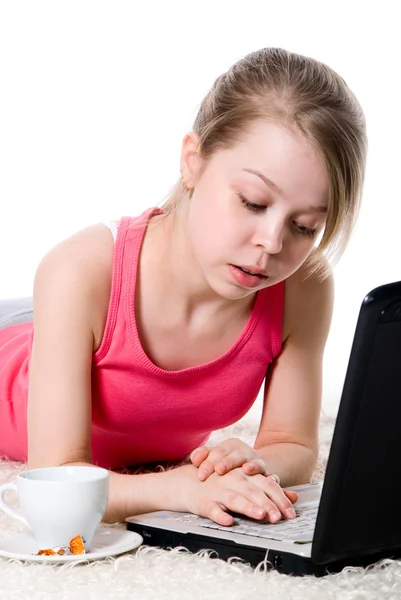 Chica alegre tumbada en el suelo y trabajando en un ordenador portátil — Foto de Stock