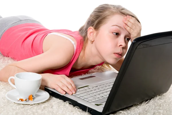 Chica joven está tirada en el suelo y trabajando en un ordenador portátil —  Fotos de Stock