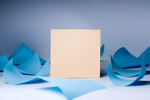 Gul tomt ark för poster bland virvlande blå blad liggande — Stockfoto
