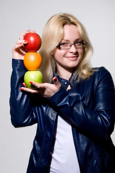 Menina em jaqueta de couro segurando uma laranja e maçã . — Fotografia de Stock