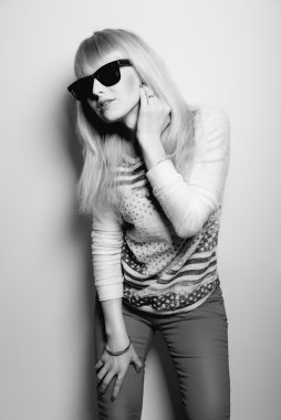 güneş gözlüklü genç ve güzel sarışın uzakta görünüyor.