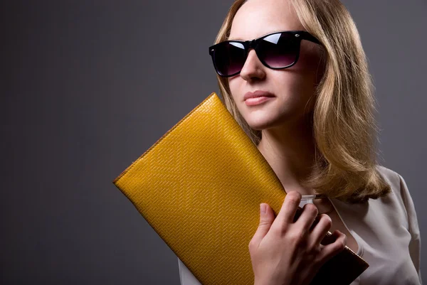 Portrait of a beautiful girl in sunglasses holding a clutch — Stock Photo, Image