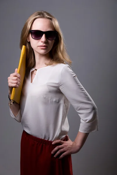 Retrato de uma menina bonita em óculos de sol segurando uma embreagem — Fotografia de Stock