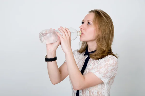 The girl drinks water from a bottle on a white — Stock Photo, Image