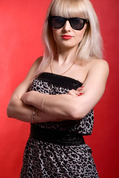 Hermosa chica en gafas de sol sobre un fondo rojo. moda mujer — Foto de Stock