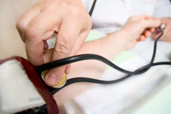 Doctor measures blood pressure in a patient — Stock Photo, Image