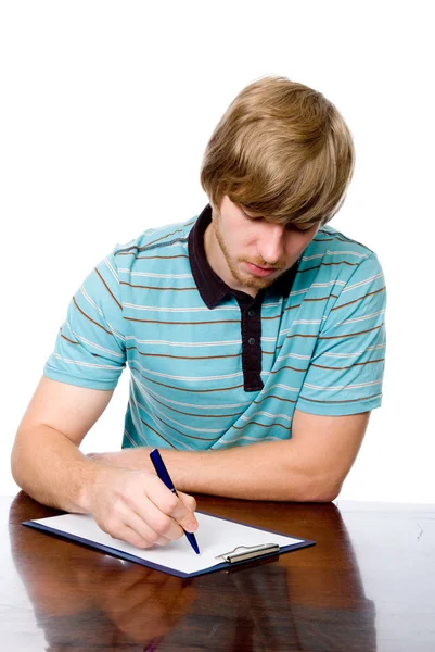 Poważny człowiek młody siedzi przy biurku z piórem w ręku. — Zdjęcie stockowe