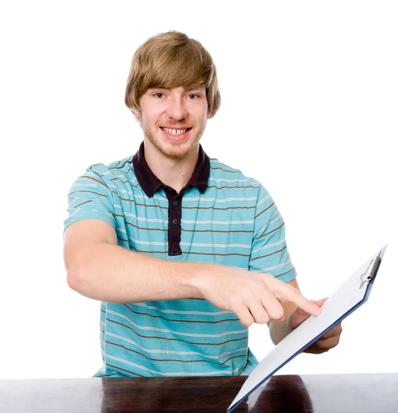 Happy young man points a finger at a blank sheet of sitting at t — Stock Photo, Image