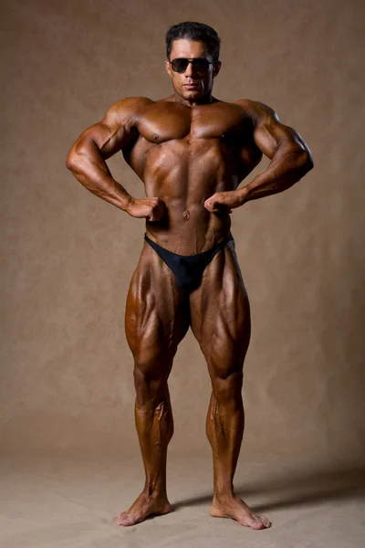 Bodybuilder flexing his muscles in studio. — Stock Photo, Image