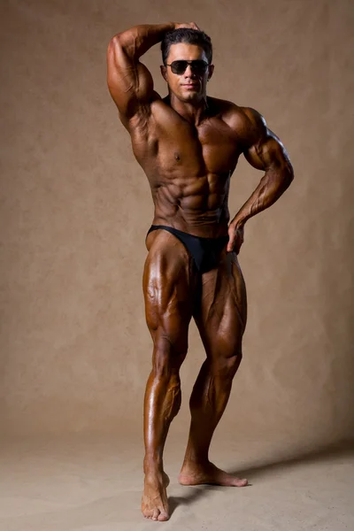 Bodybuilder flexing his muscles in studio. — Stock Photo, Image