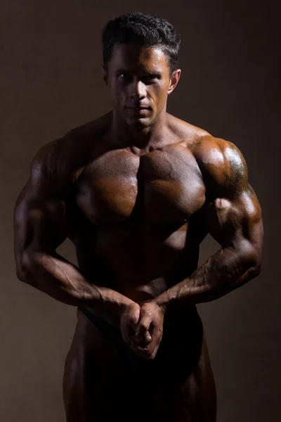 Young sports guy with a naked torso against a dark background — Stock Photo, Image